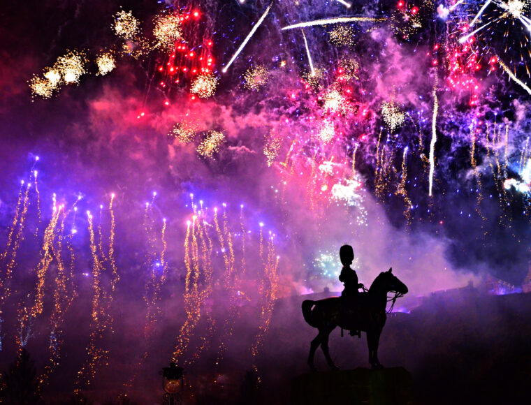 New Year fireworks at Edinburgh castle. The foreground includes a man on a horse overlooking Edinburgh New Year Fireworks.