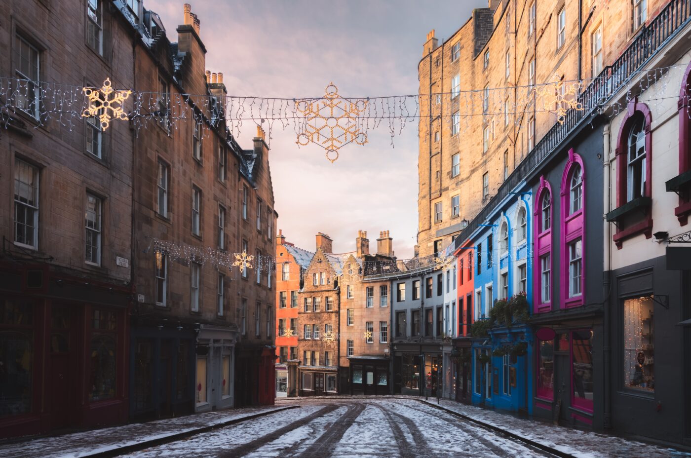 A side road covered in snow in Edinburgh at Christmas. The road includes a number of Victorian terrace properties on both sides of the road.